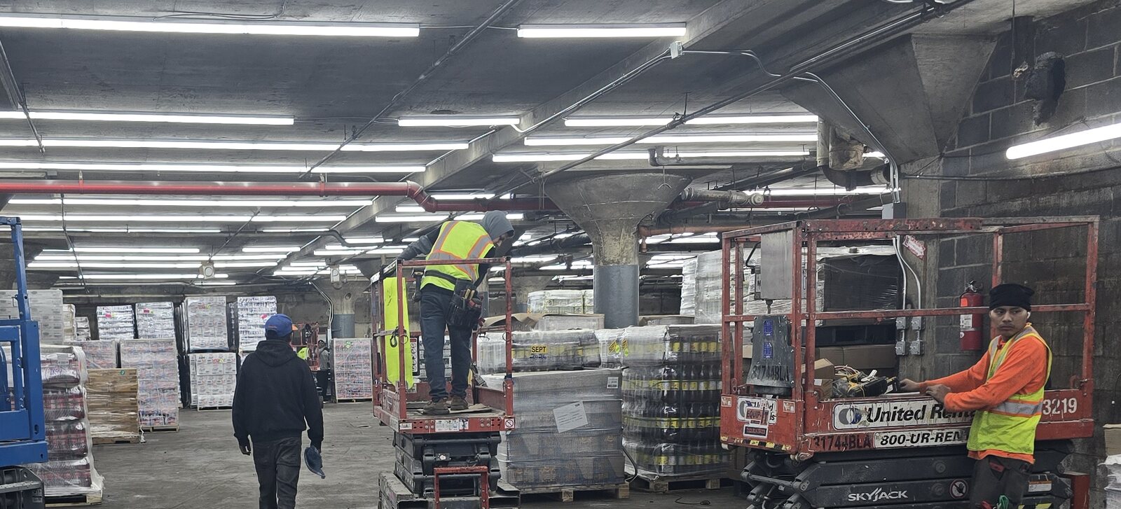 Our crew installing LED lighting from lifts in a commercial warehouse